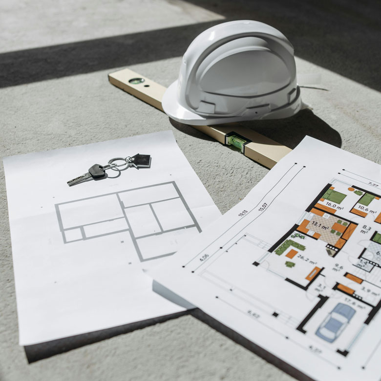 Mesa con planos de construcción y casco de seguridad, representando el asesoramiento para invertir en obra nueva