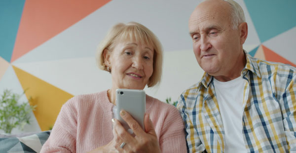 Pareja mayor mirando el móvil representando la compra de un nuevo hogar en Valencia